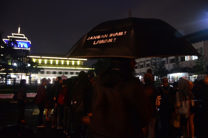 Salah satu peserta menggunakan payung hitam pada Aksi Kamisan Bandung, Jum’at (23/6/2016) di depan gerbang Gedung Sate, Bandung. Payung hitam berisi tulisan Jangan Diam! Lawan! Menjadi tanda Aksi Kamisan Bandung merindukan tegaknya keadilan di Indonesia. (SUAKA/ Mohammad Aziz Pratomo)