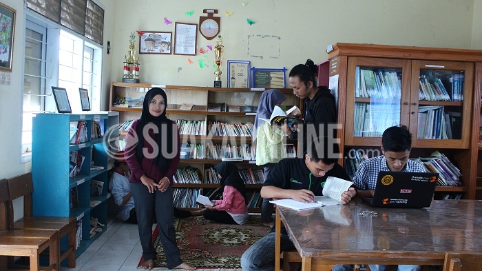 Lia Yulianti (kerudung hitam) saat berada di perpustakaan Taman Pamekar, Sukabumi, Minggu, (11/09/2016). Kecintaannya terhadap membaca membuat ia mumutuskan untuk mengelola perpustakaan sejak pertengahan November 2002 lalu. (SUAKA/Purna Irawan)