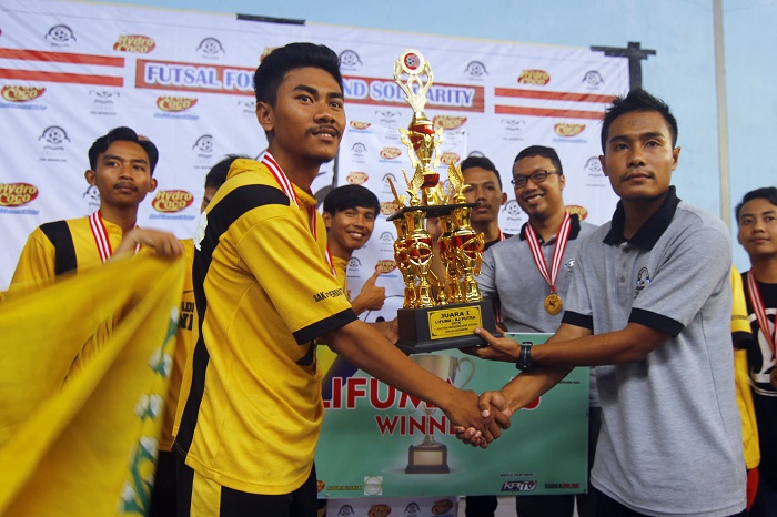 Ketua umum Unit Kegiatan Mahasiswa (UKM) Liga dan Futsal, Idan Sutisna (kanan) memberikan tropi juara pertama Liga Futsal Mahasiswa Antar Jurusan Lifuma AJ) 2016 kepada kapten tim futsal Jurusan Administrasi Negara (kiri), Sabtu (26/3/2016) di Mayasari Sport Hall. AN juarai Lifuma AJ setelah mengalahkan Jurusan KPI melalui drama adu penalti. (Mohammad Aziz Pratomo/ Magang)